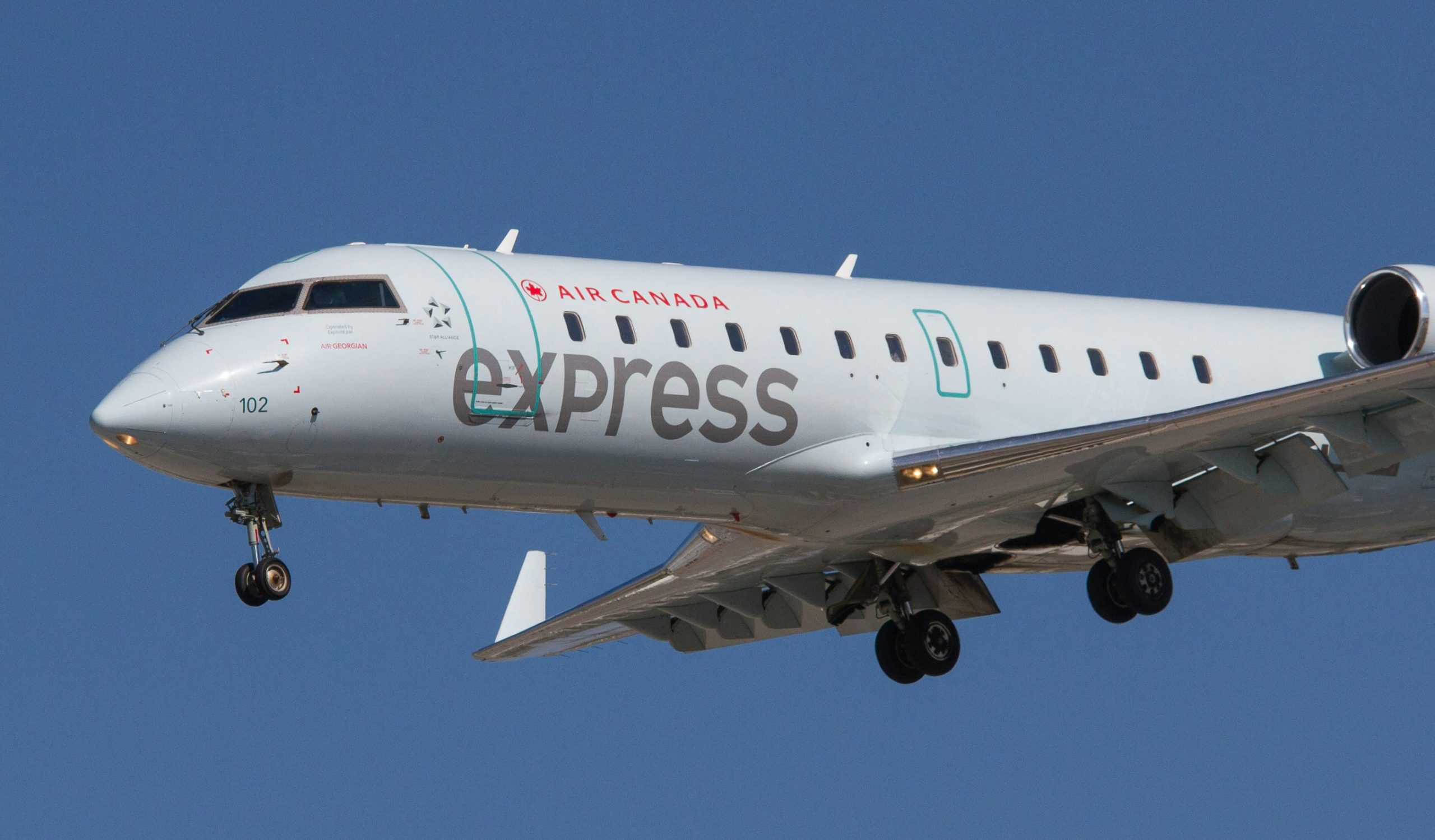 express entry A large Air Canada airplane flying in a clear blue sky, with visible jet engines and aircraft details.