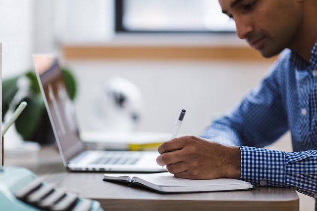 Person working on immigration paperwork and LMIA compliance at a desk with a laptop and notebook.
